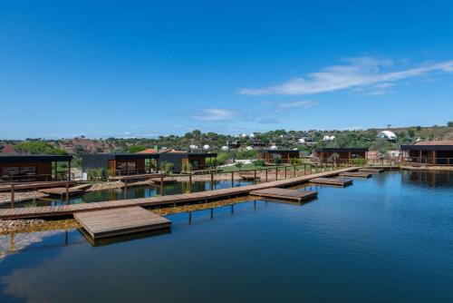 a dock on a body of water with houses at wecamp Reserva Alecrim in Santiago do Cacém