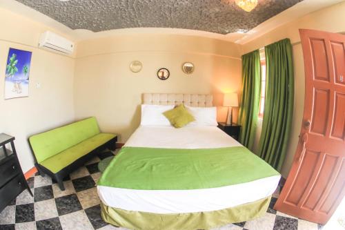 a bedroom with a green bed and a green bench at Kaiser Hotel- Negril West End in Negril