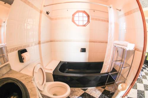 a bathroom with a tub and a toilet and a sink at Kaiser Hotel- Negril West End in Negril