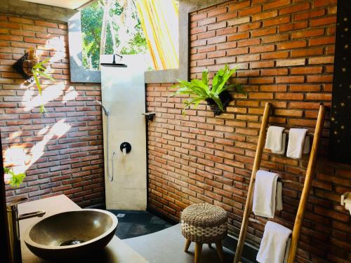 a bathroom with a sink and a brick wall at Coco Garden Pool Villas in Kubutambahan