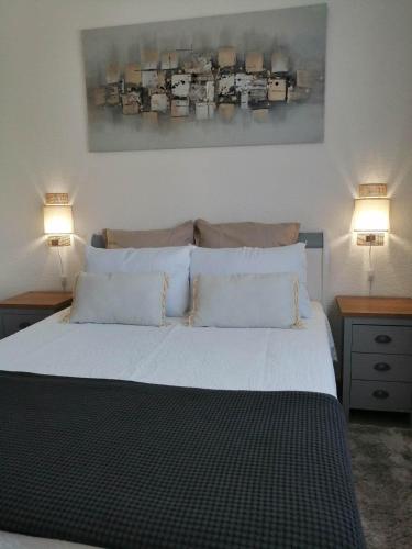 a bedroom with a large white bed with two lamps at Alicia in Camélas