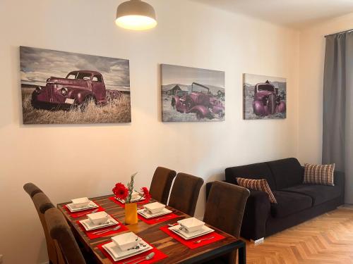 a living room with a table and a couch and some paintings at Riverbridge Apartments Prague in Prague