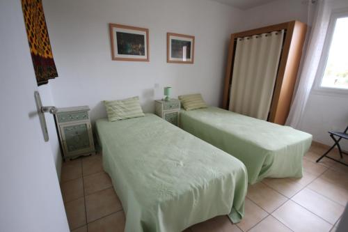 une chambre avec deux lits et une fenêtre dans l'établissement Belle villa climatisée 3 chambres, véranda, terrasse arborée dans résidence sécurisée avec piscine commune 800m de la mer WIFI Un vrai Havre de Paix LRCS98, à Portiragnes
