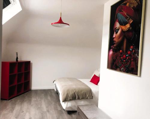 a bedroom with a painting of a woman on the wall at Aux Couleurs d'Alsace in Ostwald