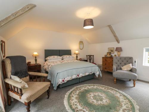 a bedroom with a large bed and two chairs at The Cottage in Highbridge
