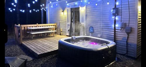 a jacuzzi tub sitting on a deck next to a building at Comtemporary, Confortable, Well Appointed Home. in Tobyhanna