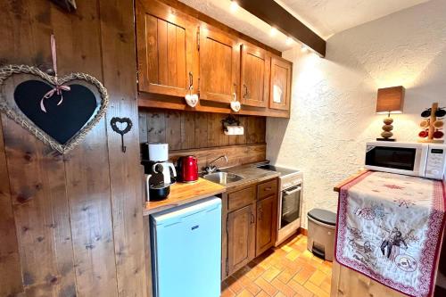a small kitchen with wooden cabinets and a refrigerator at Cosy studio with garden and view of Mont Blanc in Saint-Gervais-les-Bains