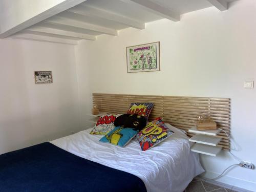 Una cama con almohadas y un osito de peluche. en Mérig'home Chambre BD climatisée dans maison avec piscine au calme en ville, SdB & toilettes privés, en Angulema