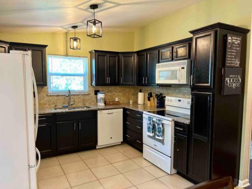 une cuisine avec des armoires noires et des appareils blancs dans l'établissement Cozy Coastal Cottage in Heart of St. Augustine, à Saint Augustine