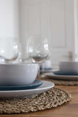 a wooden table with plates and wine glasses on it at Azure Haven - Bournemouth in Bournemouth
