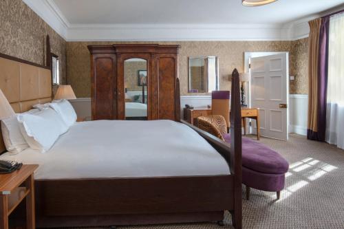 a bedroom with a large bed and a desk at Norton Park Hotel, Spa & Manor House - Winchester in Sutton Scotney