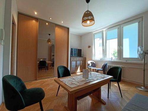 uma sala de estar com uma mesa e cadeiras verdes em Apartament Baltica Nawigator em Gdynia