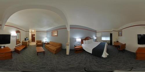 a hotel room with a bed and a living room at Budget Host Inn and Suites Cameron in Cameron