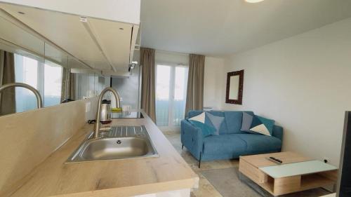 a kitchen with a sink and a blue couch at Joli 2 pièces tout confort Paris Parc des expositions Villepinte in Villepinte