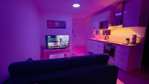 a purple living room with a couch and a kitchen at Joli 2 pièces tout confort Paris Parc des expositions Villepinte in Villepinte