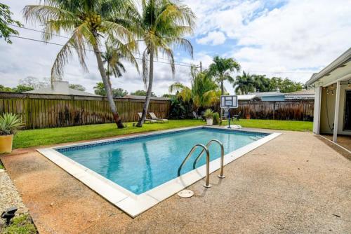 a swimming pool in a backyard with palm trees at Boynton 3 2 Pool House in Boynton Beach