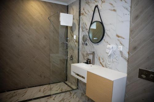 een badkamer met een wastafel en een douche met een spiegel bij хотел ADDRESS in Ravda