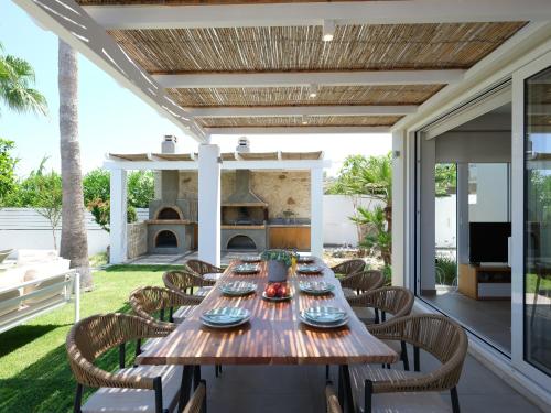 an outdoor dining room with a table and chairs and a fireplace at Sea La Vie in Adelianos Kampos