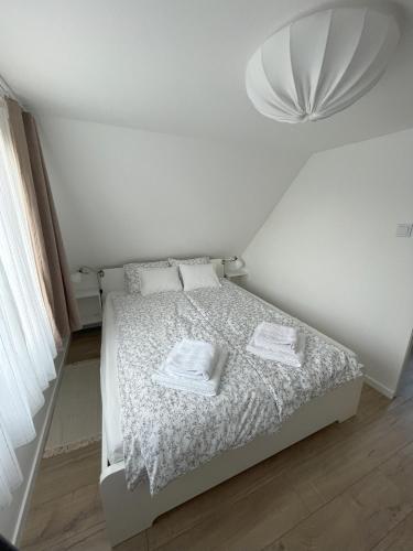 a white bedroom with a bed with two towels on it at Mi szél hozott in Lipót