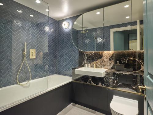 a bathroom with a tub and a toilet and a sink at Mayfair - Peterson House by Viridian Apartments in London