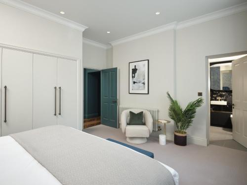 een slaapkamer met een wit bed en een stoel bij Mayfair - Peterson House by Viridian Apartments in Londen