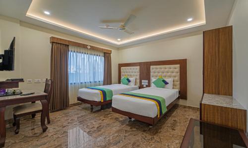 a hotel room with two beds and a desk at Treebo Aaravi Residency, 800 Mtrs From Promenade Beach in Puducherry