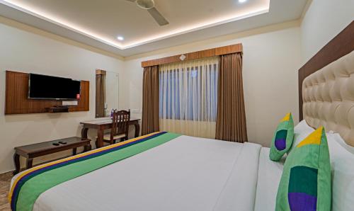 a bedroom with a bed and a desk and a television at Treebo Aaravi Residency, 800 Mtrs From Promenade Beach in Puducherry