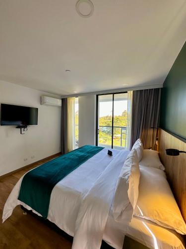 a bedroom with a large bed with a large window at Hotel Lagoon in Rionegro