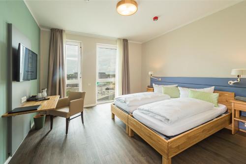 een slaapkamer met een bed, een bureau en een bureau bij Hotel Neues Pastorat in Heiligenhaus