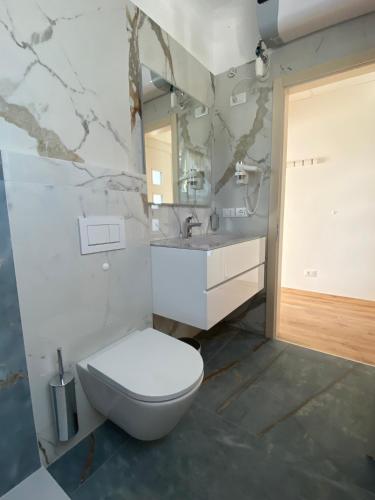 a bathroom with a white toilet and a sink at Maison Eglantine in Mezzana