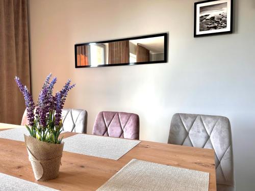 a dining room table with a mirror and purple flowers at Domy wakacyjne WELLE in Kołczewo