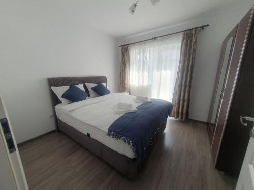 una camera da letto con un letto con cuscini blu e una finestra di Flat in Sibiu 20 min to Sibiu Airport a Sibiu