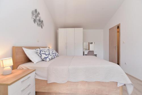 a white bedroom with a large bed and a desk at House Liznjan 2273 in Ližnjan