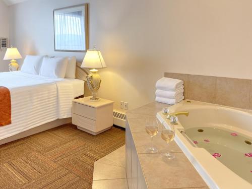 a hotel room with a bed and a tub with wine glasses at Coast Hinton Hotel in Hinton