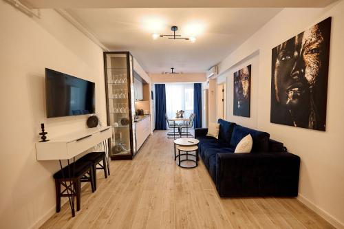 a living room with a blue couch and a tv at Infinity by Sea Apartment Beach Resort - parking in Mamaia