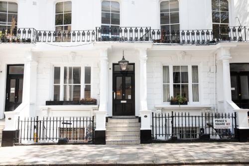una casa blanca con una puerta negra y una valla en Princes Square, en Londres