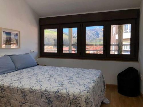 a bedroom with a bed and windows with a view at APARTAMENTO El Roxu 2 in Arriondas