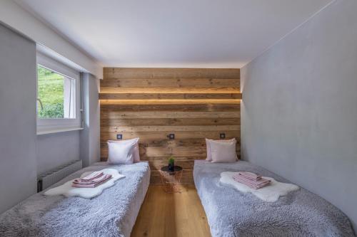 - 2 lits dans une chambre avec un mur en bois dans l'établissement Lucky Fox, à Loèche-les-Bains