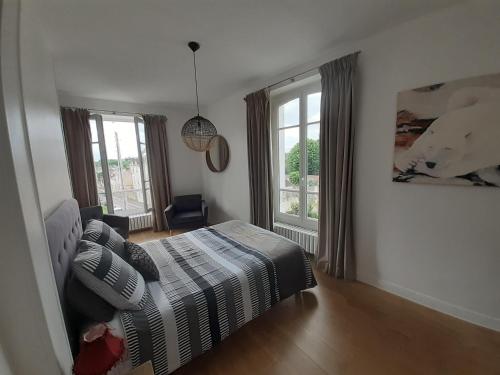 a bedroom with a bed with a striped blanket and two windows at centre ville, chambre indépendante 20m2 et sa salle de bain privée in Nogent-le-Rotrou