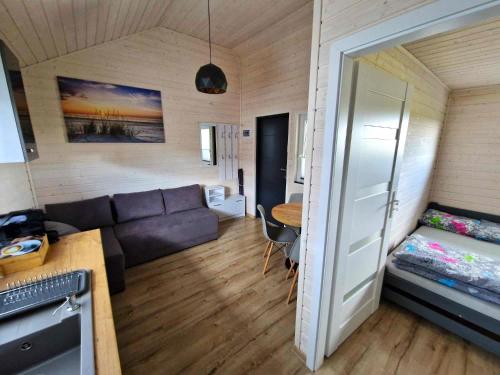 uma sala de estar com um sofá e uma mesa em Fajne domki em Ustronie Morskie