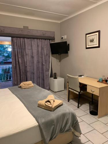 a bedroom with a bed and a desk and a desk at Hotel Pension Casa Africana in Windhoek