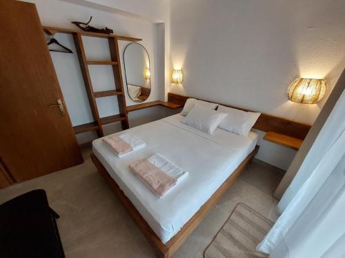 a small bedroom with a white bed with a mirror at Seastone in Ierissos