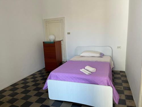 Dormitorio pequeño con cama con manta morada en Palazzo Storico Mileto, en Mileto