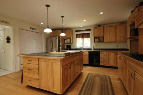 a large kitchen with wooden cabinets and a large island at Beautiful Spacious Home w/ Game Room. in Gilford