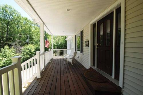 a front porch of a house with a flag at Beautiful Spacious Home w/ Game Room. in Gilford