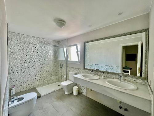 a bathroom with two sinks and a toilet and a mirror at Turquesa 3 Fuerteventura in Corralejo
