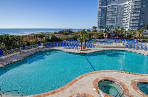 ein großer Swimmingpool mit blauen Stühlen und der Strand in der Unterkunft Sea Watch Resort in Myrtle Beach