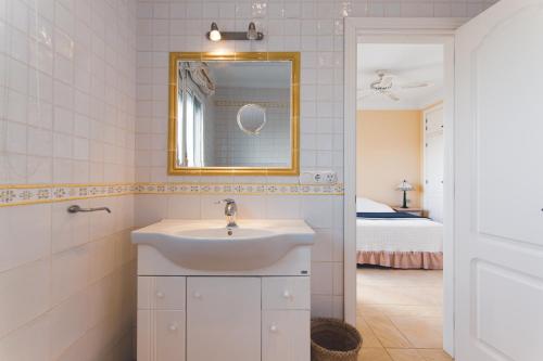 ein Bad mit einem Waschbecken, einem Spiegel und einem Bett in der Unterkunft Casa Miguel in Frigiliana