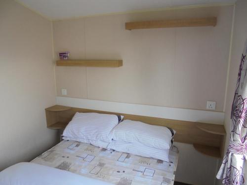 a small bedroom with a bed with white sheets at Kingfisher : Vacation III:- 6 Berth, Close to site entrance in Ingoldmells
