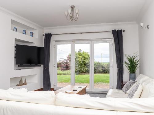 a living room with a white couch and a large window at Took Some Doing in Bodmin